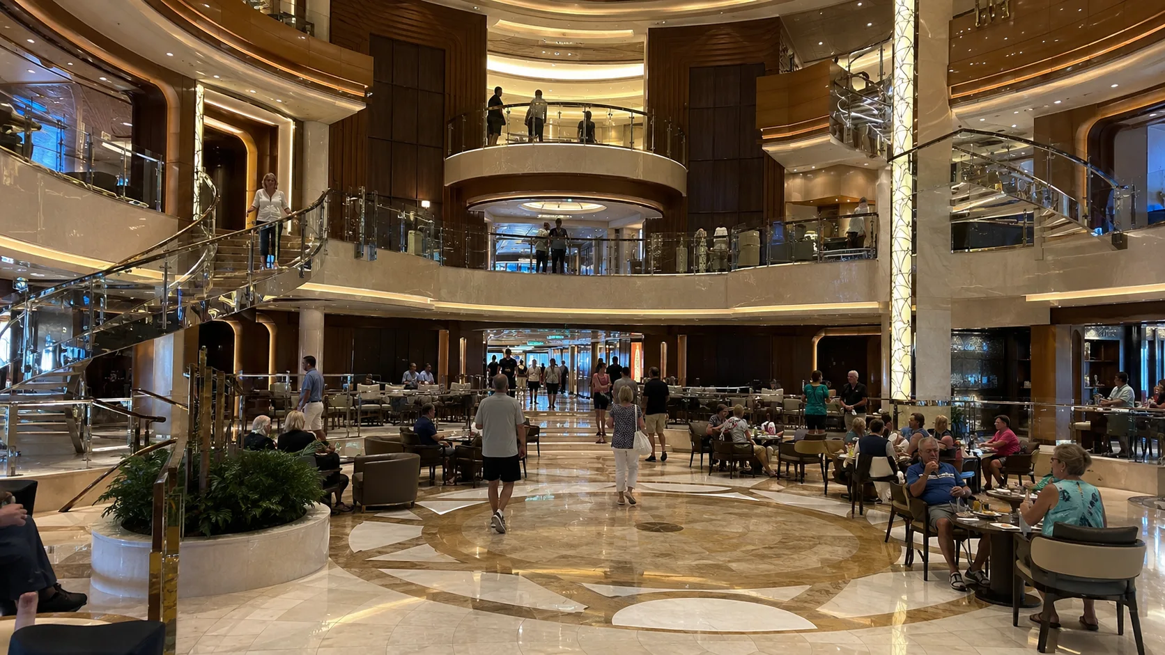 Cruise ship atrium with cafe seating and curved balconies