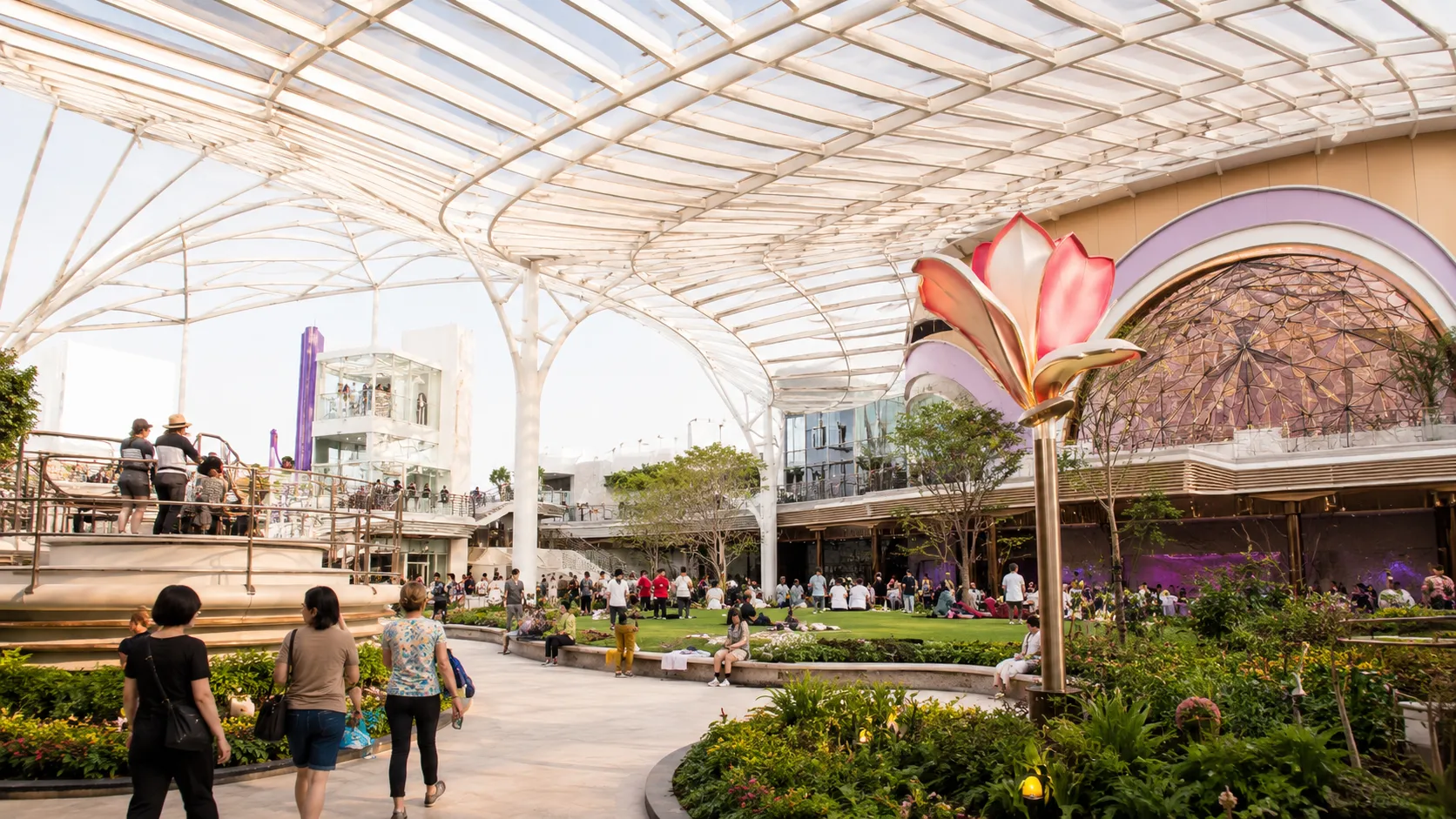 Landscaped cruise ship promenade beneath a curved glass canopy