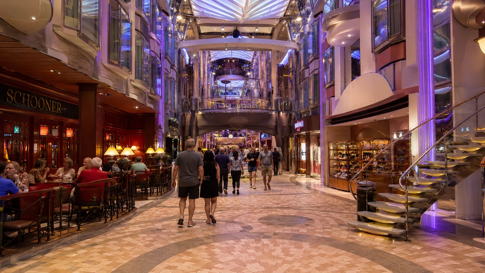 Passengers walking through a grand indoor cruise promenade