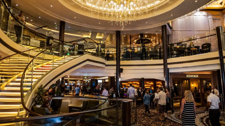 Grand cruise ship atrium with curved stairs and a crystal chandelier
