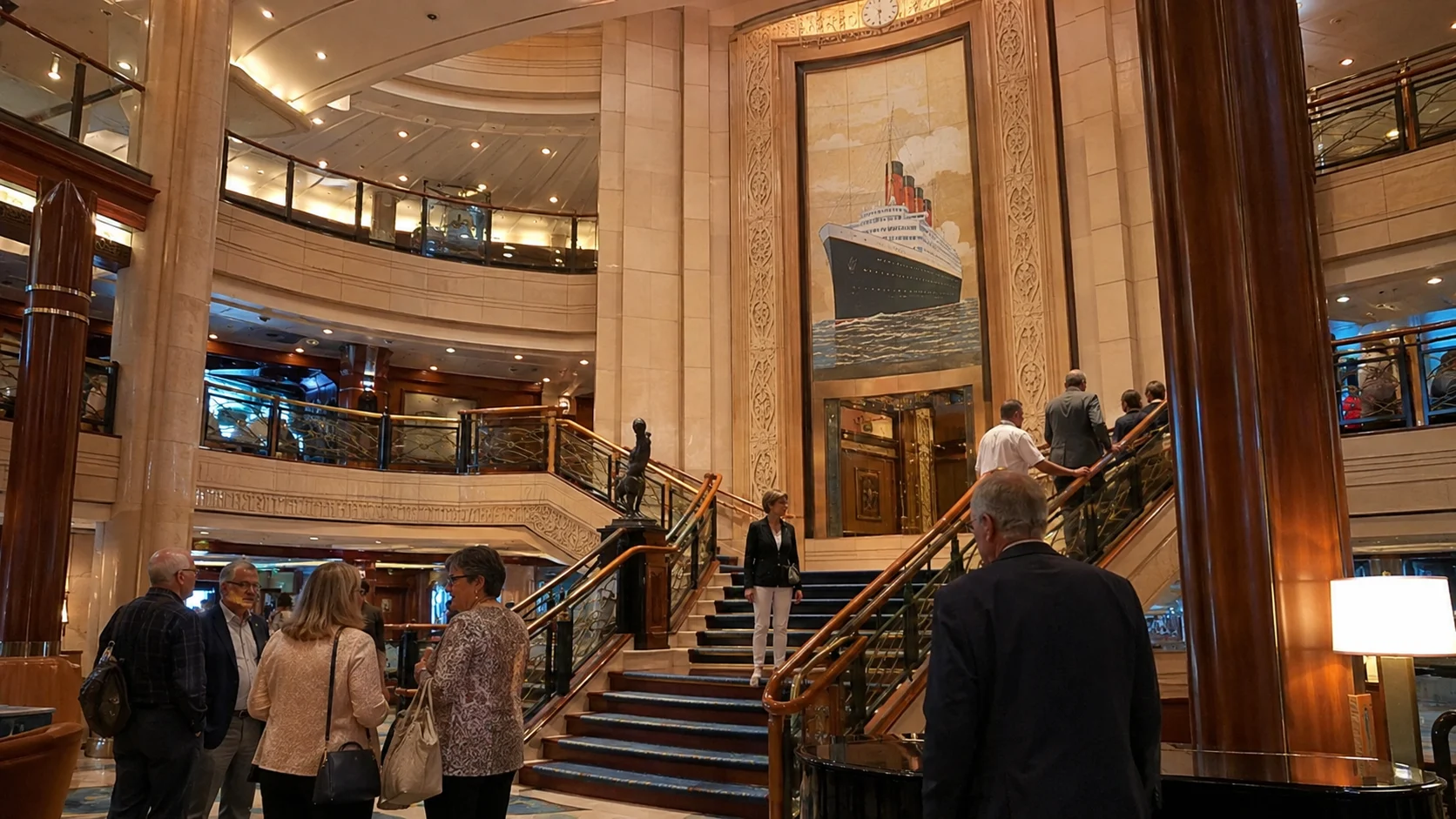 Grand cruise ship lobby with twin staircases and wood paneling