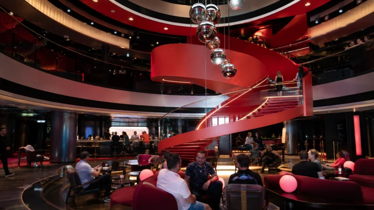 Red spiral staircase and lounge seating in a cruise ship atrium