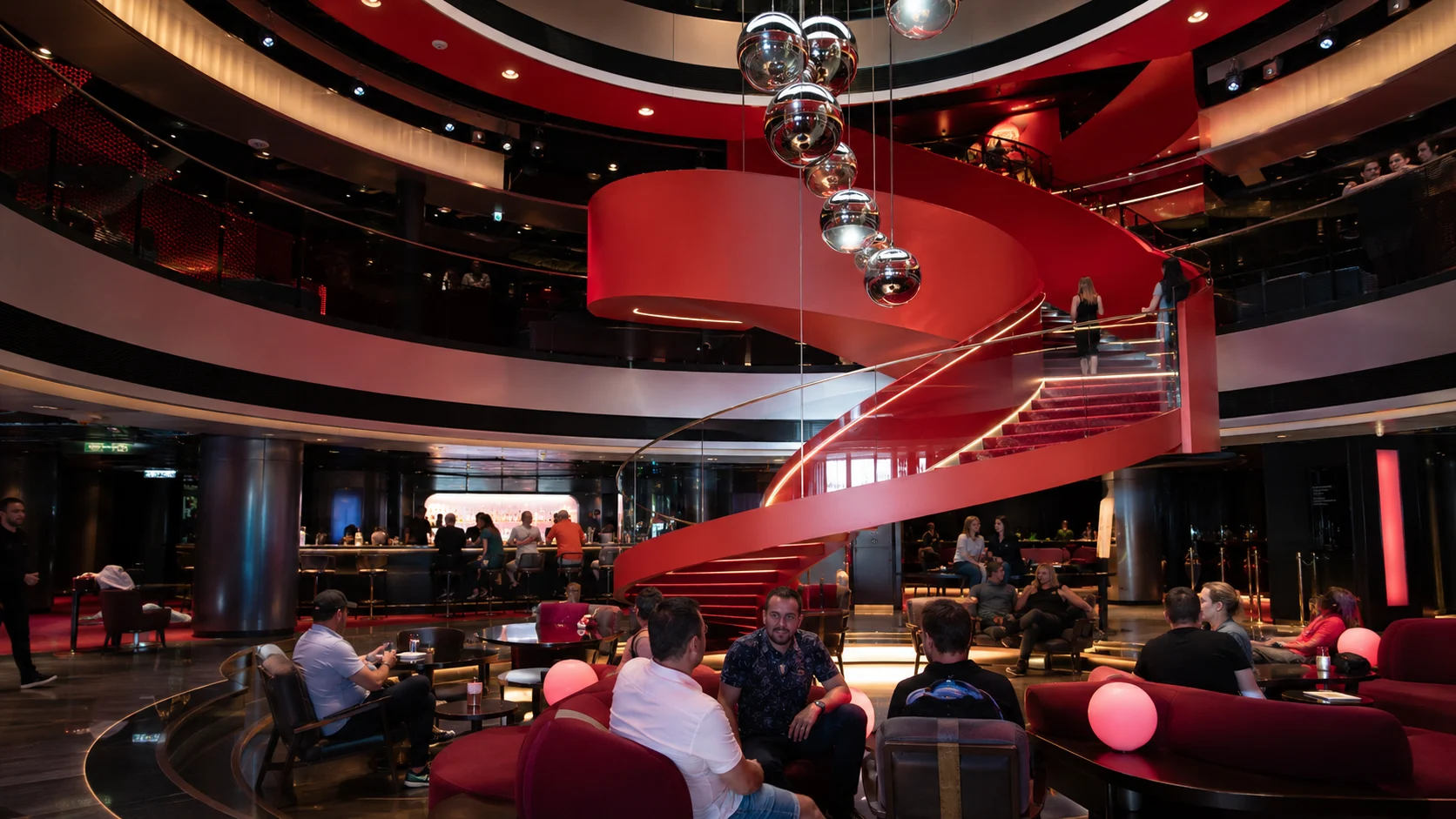 Red spiral staircase and lounge seating in a cruise ship atrium