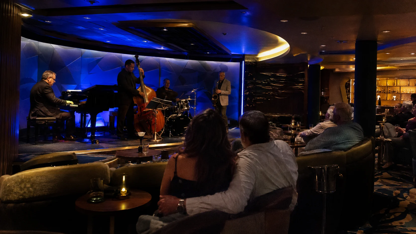 Jazz trio performing in a dim blue-lit cruise ship lounge