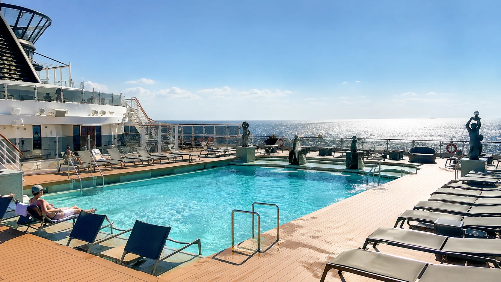 Quiet outdoor cruise ship pool deck with rows of loungers