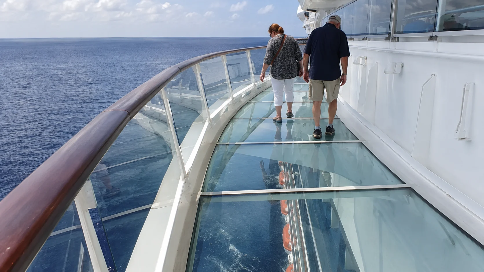 Passengers walking across the glass-floored SeaWalk above the ocean