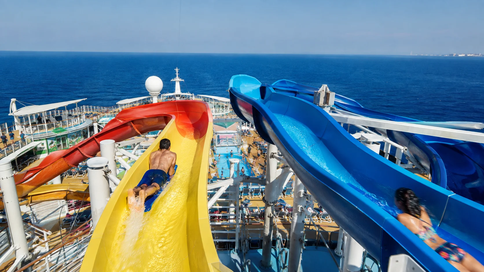 Yellow and blue waterslides twisting above a cruise ship deck