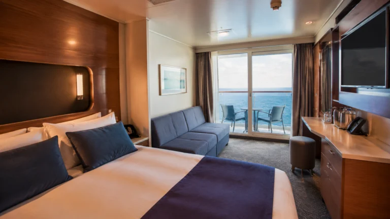 Balcony cabin with a blue sofa, wall-mounted television and ocean view