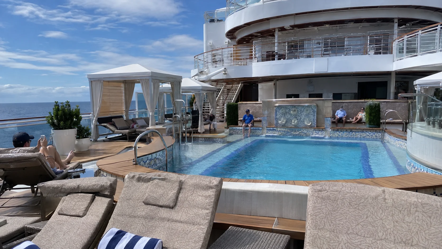 Small upper-deck pool surrounded by cushioned loungers