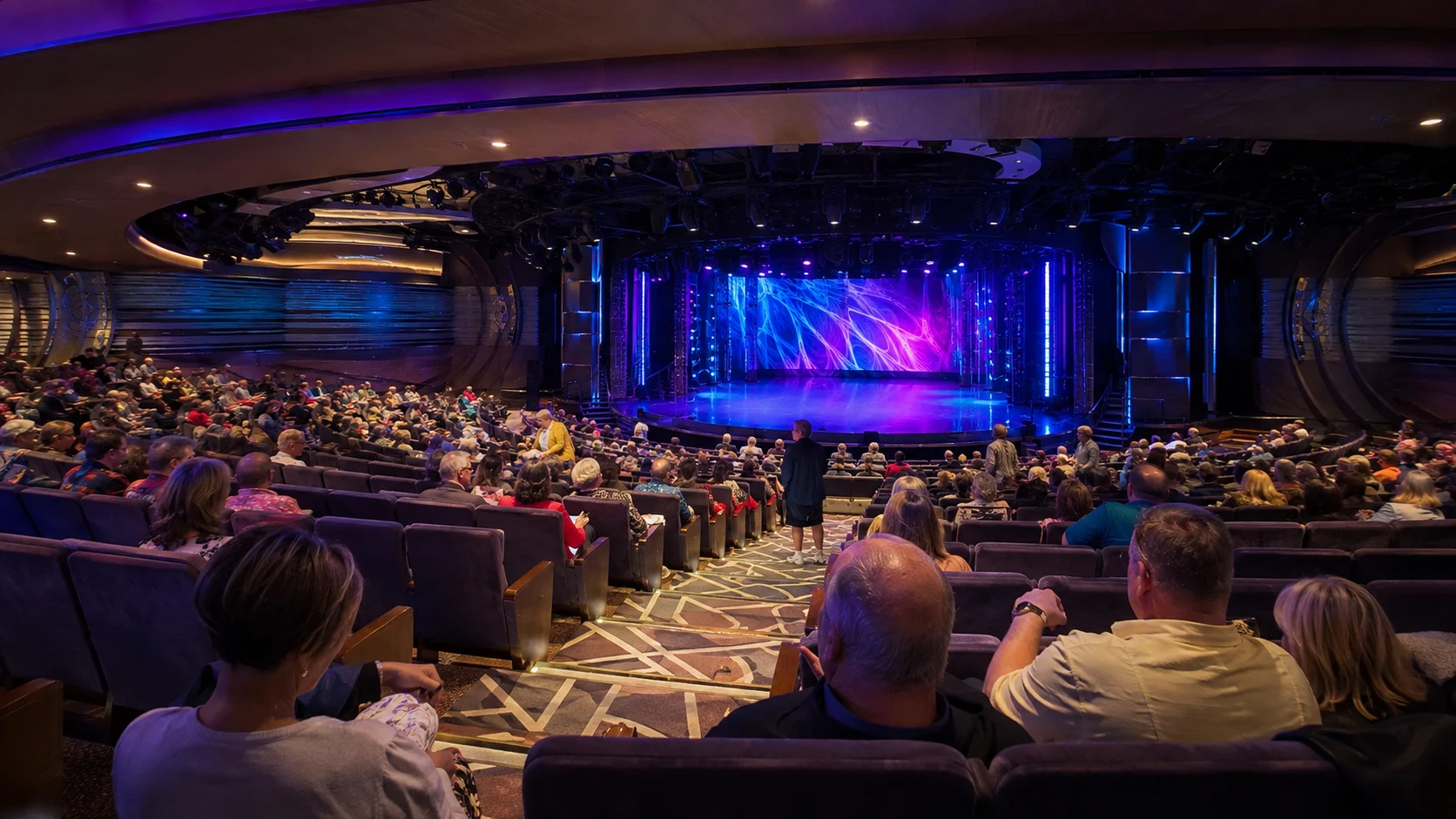 Audience watching a colorful stage show in a cruise ship theater