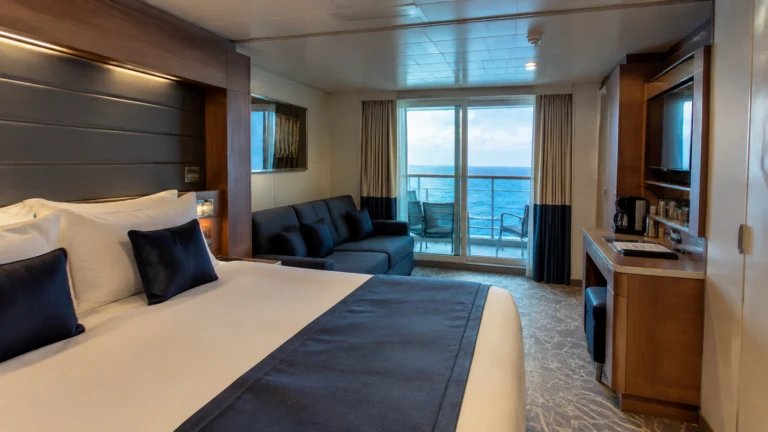 Balcony cabin with a navy bed runner, blue sofa and ocean view