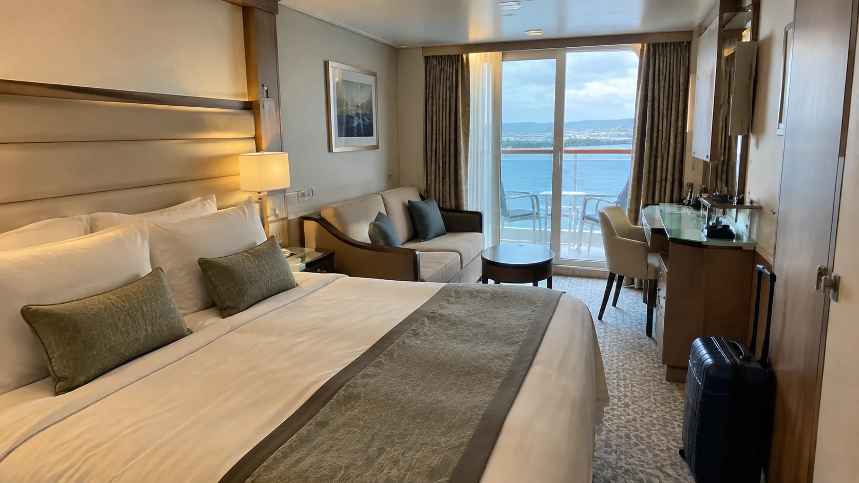 Balcony cruise cabin with a double bed and gray sitting area