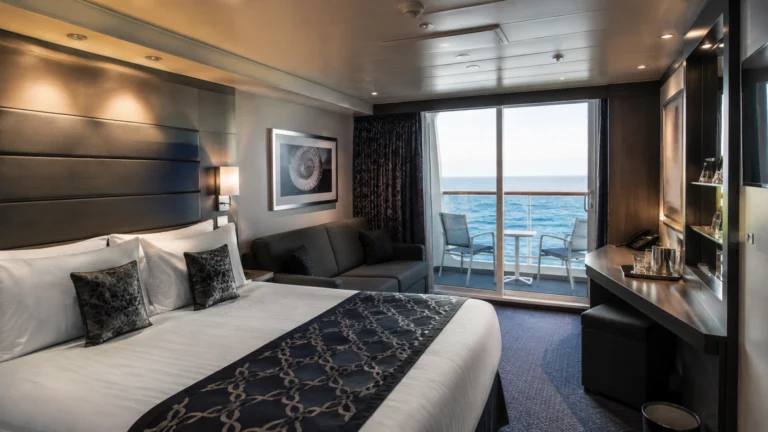 Balcony cabin with a patterned navy bed runner and desk by the window