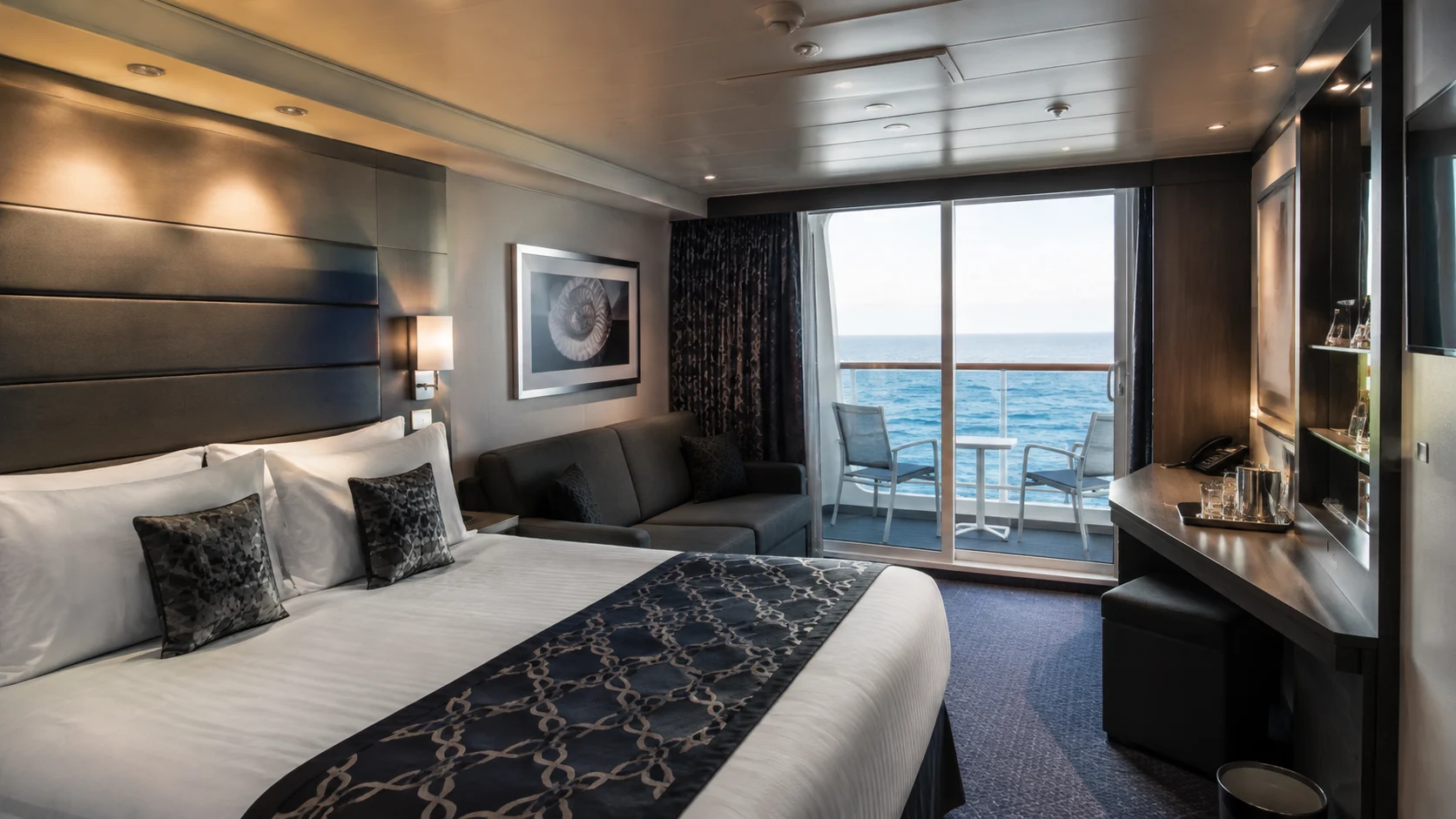 Balcony cabin with a patterned navy bed runner and desk by the window