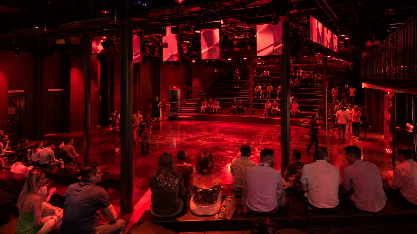 Audience watching a live performance in a red-lit nightclub