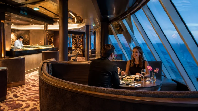 Couple dining beside curved panoramic windows on a cruise ship