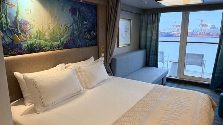 Cruise cabin with a double bed, underwater mural, sofa, and balcony