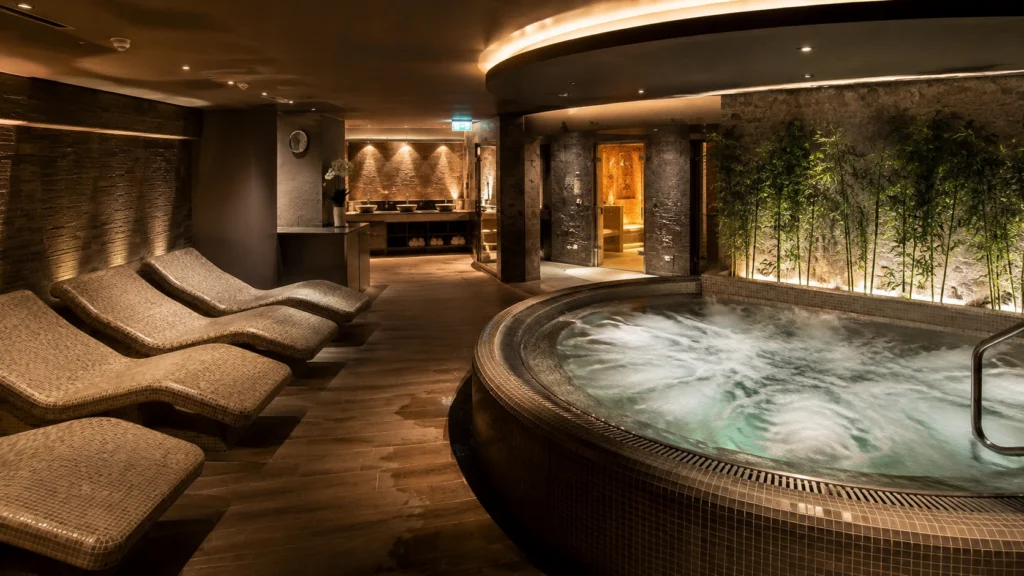 Dimly lit spa with a round whirlpool and heated loungers