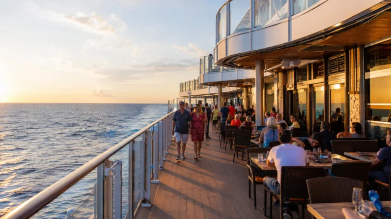 Passengers walking along an oceanfront promenade with outdoor dining