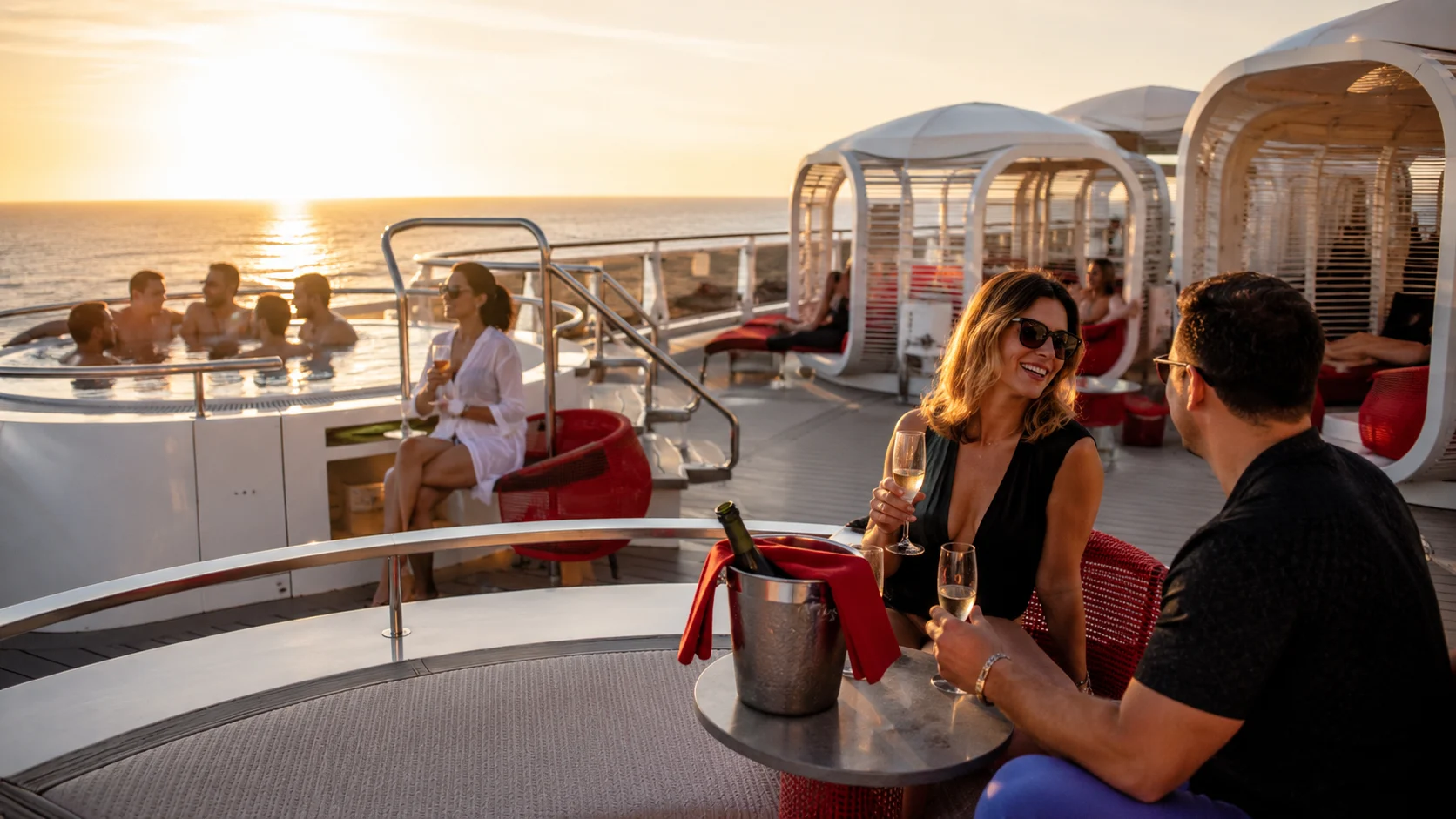 Couple sharing drinks on an open cruise ship deck at sunset
