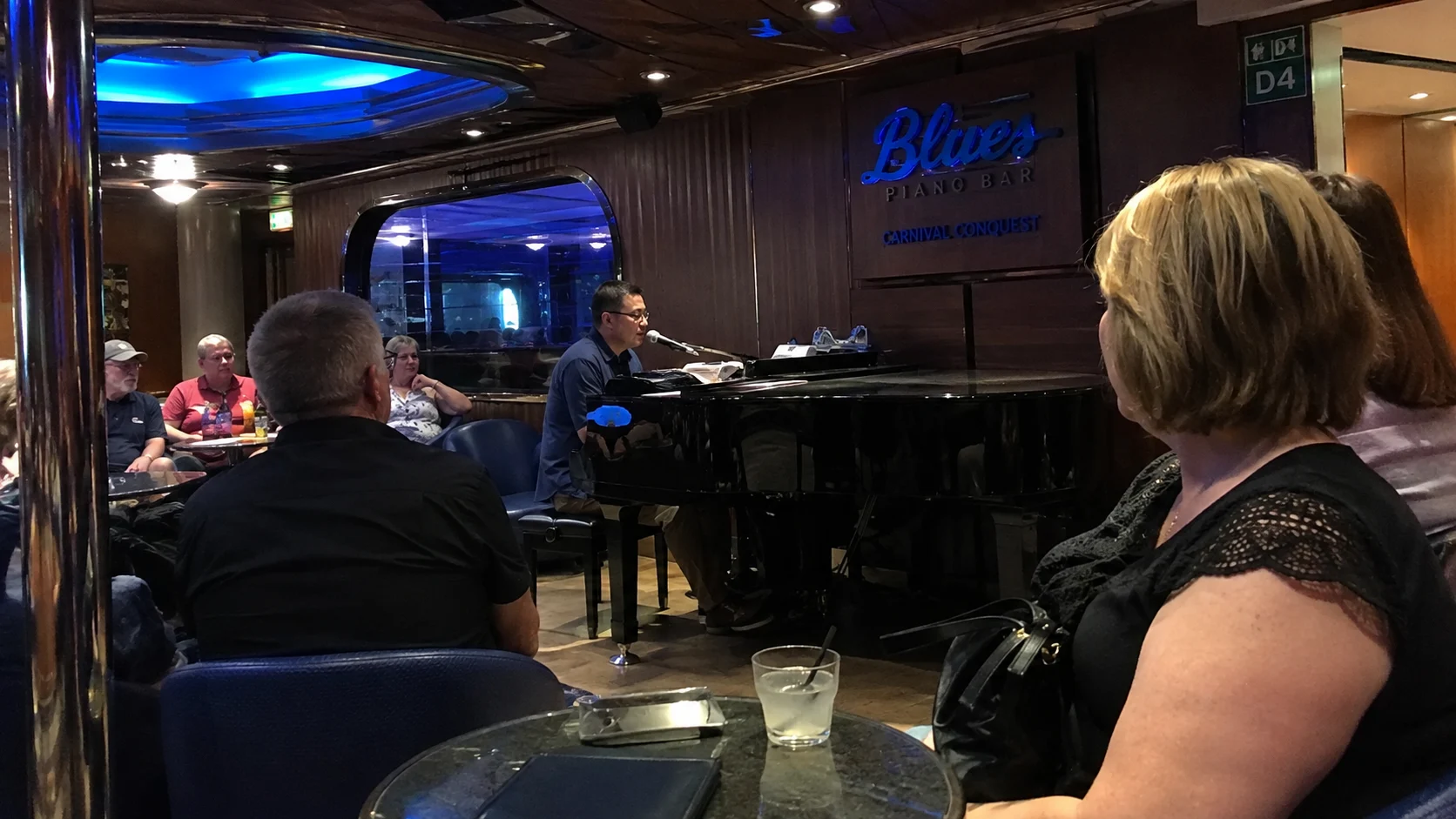 Passengers listening to a pianist in Blues Piano Bar aboard Carnival Conquest