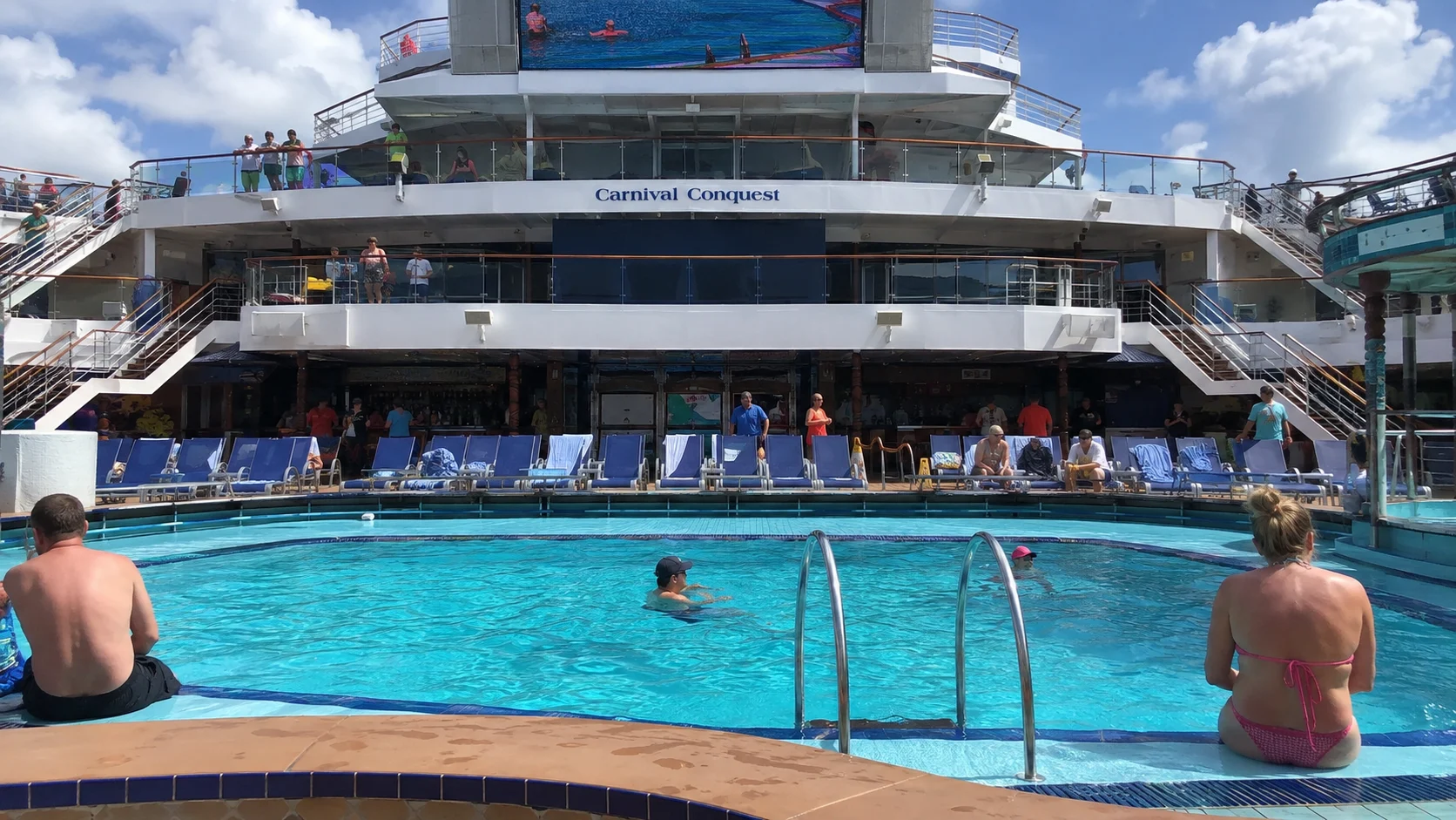 Passengers around the outdoor pool aboard Carnival Conquest