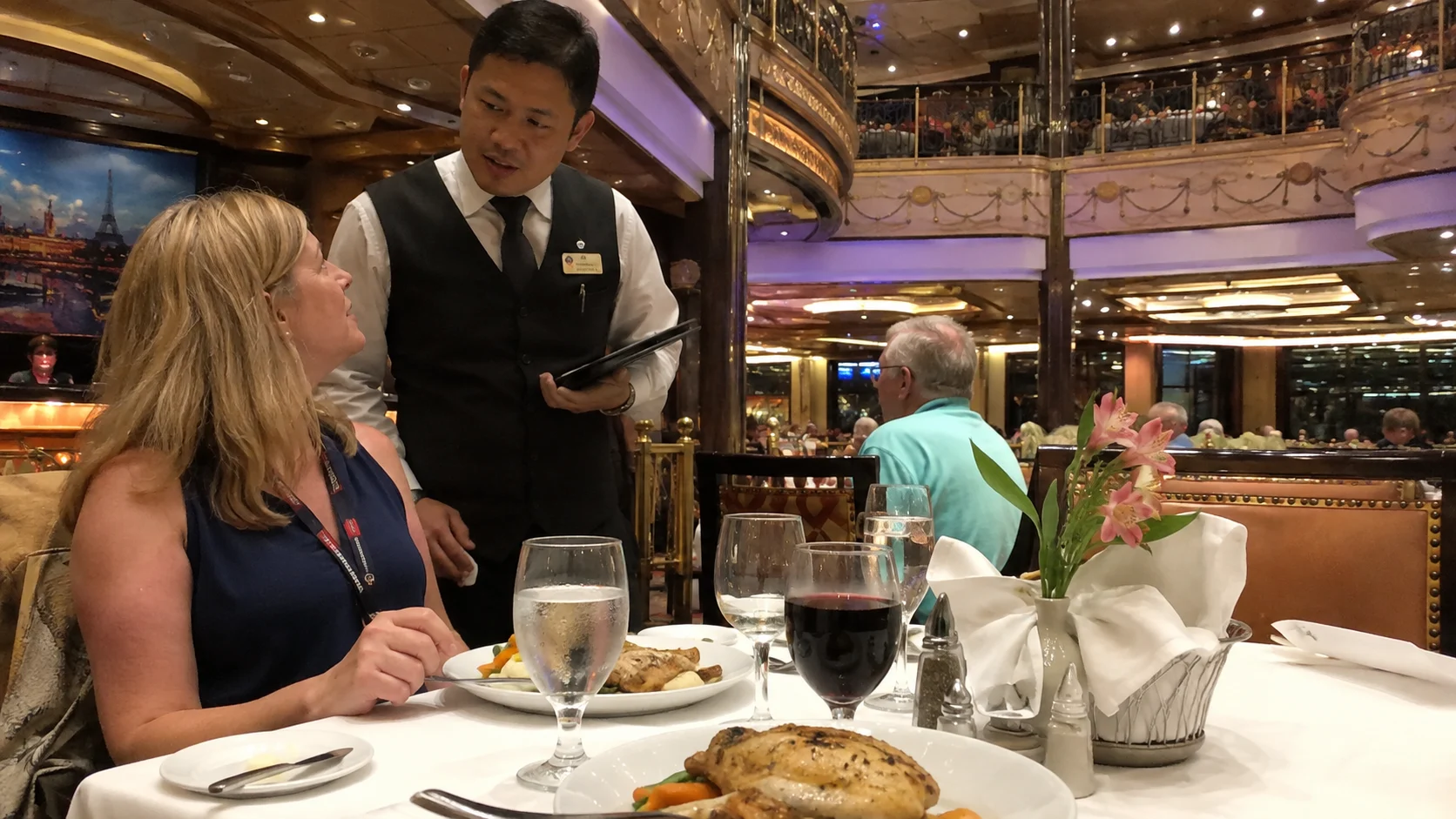 Waiter speaking with a passenger at a cruise ship dining table