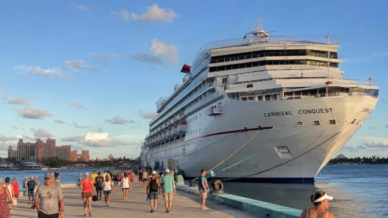 Passengers walking along a pier beside Carnival Conquest