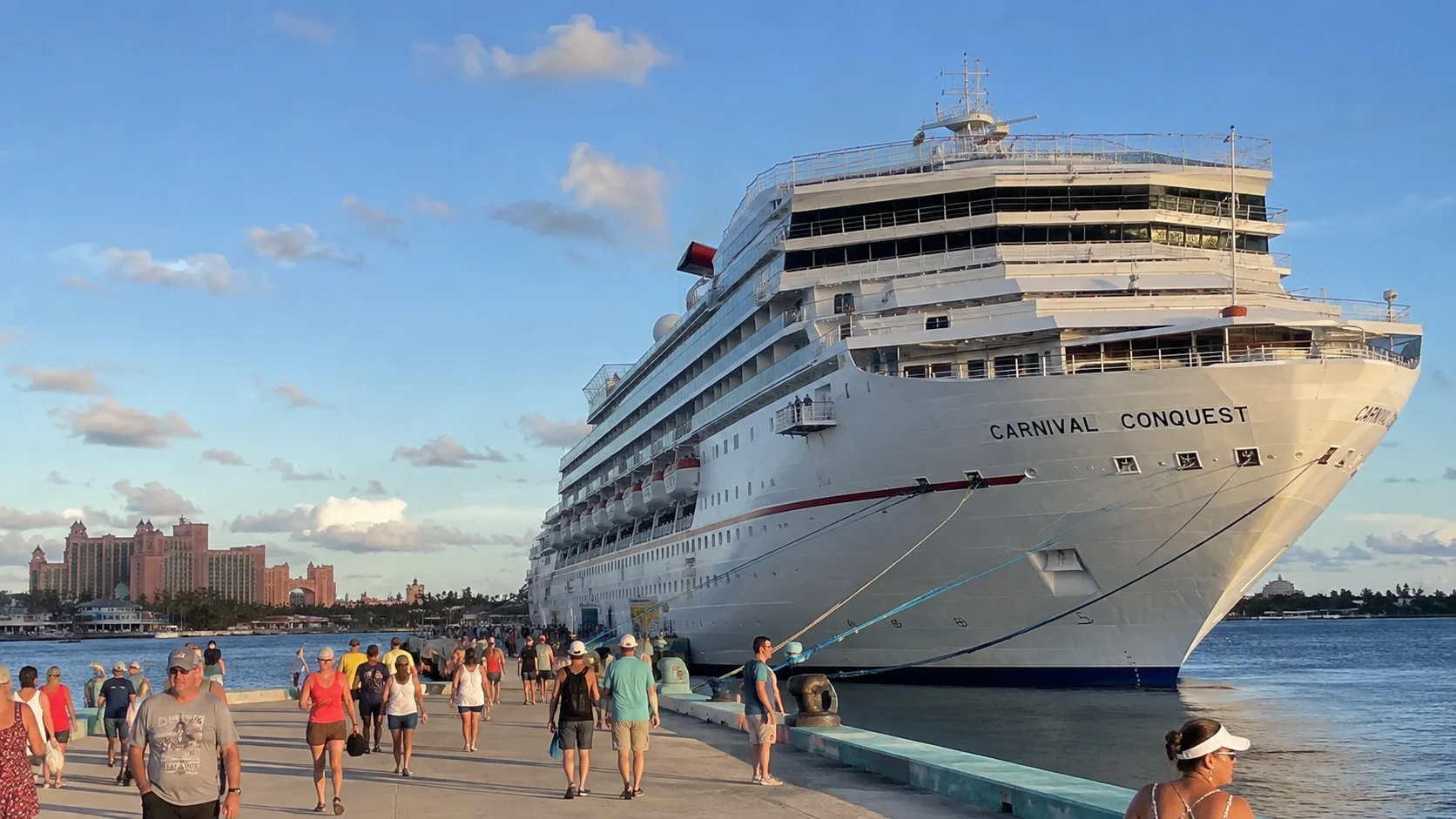 Passengers walking along a pier beside Carnival Conquest