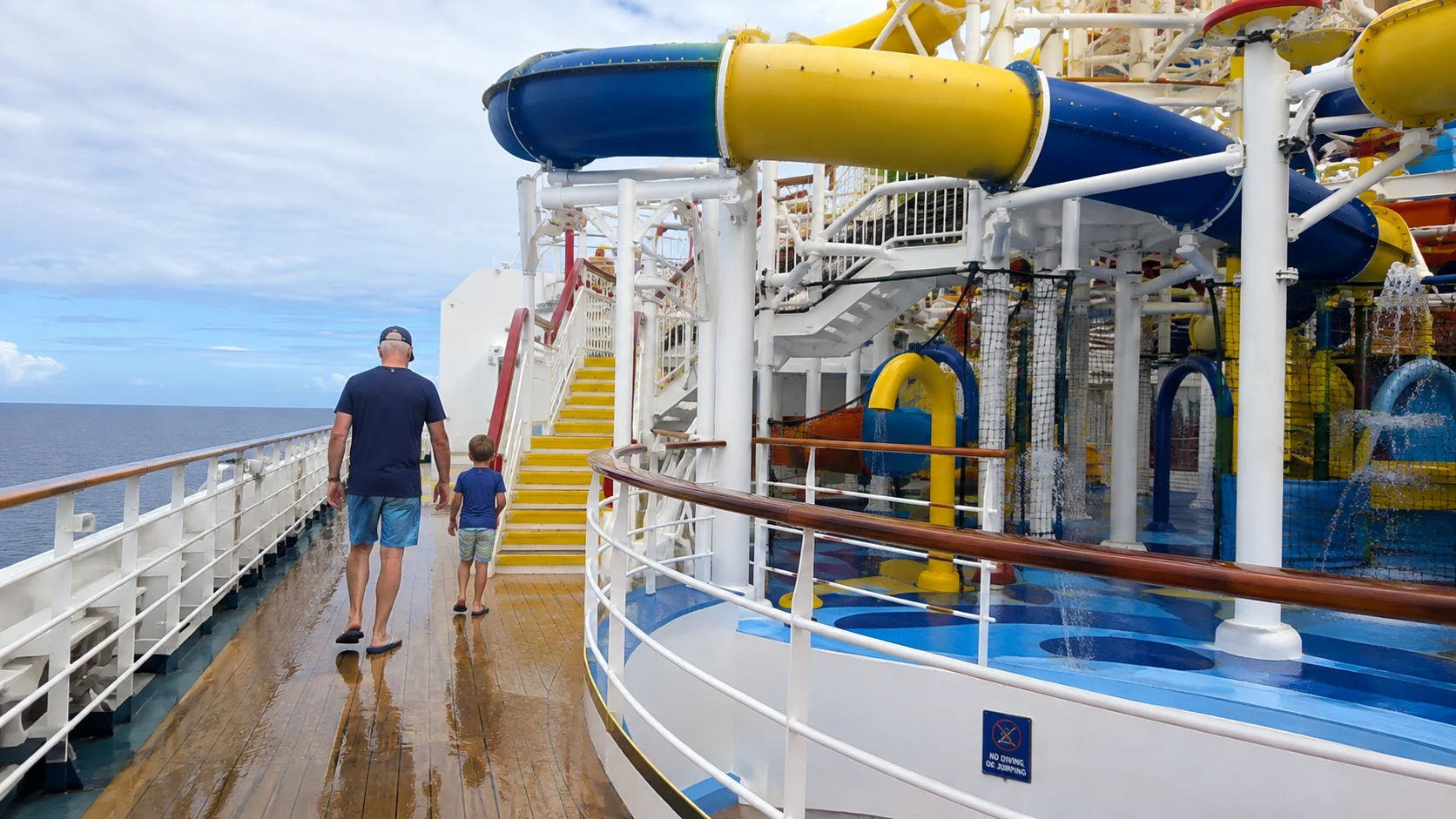 Passenger walking on a wet upper deck near colorful waterslide structures