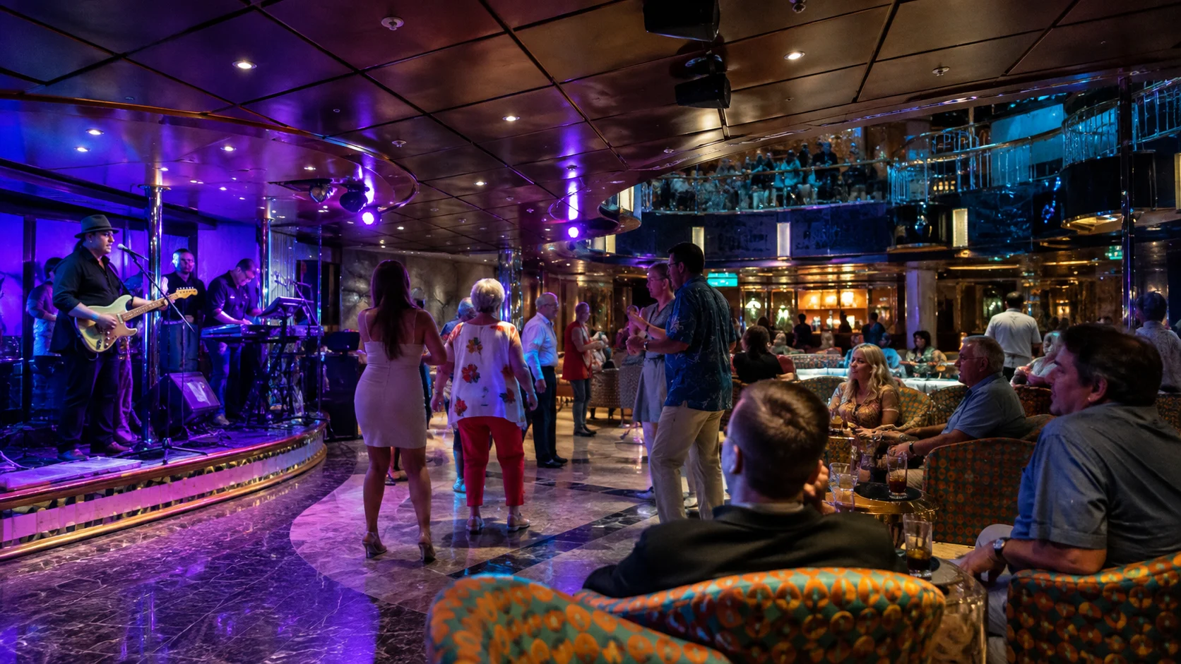 Passengers dancing to live music in a colorful cruise ship lounge