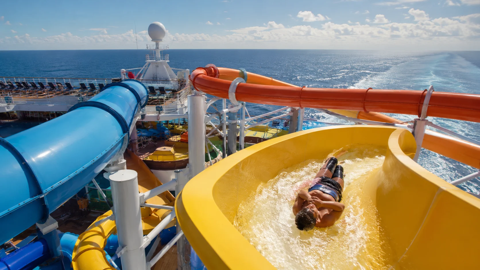 Passenger riding a yellow waterslide on a cruise ship