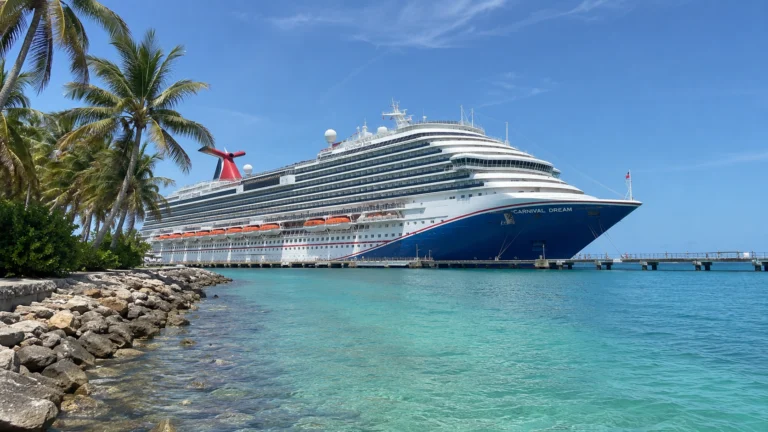 Carnival cruise ship docked beside a palm-lined tropical shore
