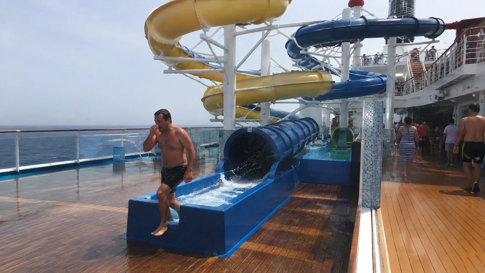 Man stepping out of a blue waterslide on a cruise ship