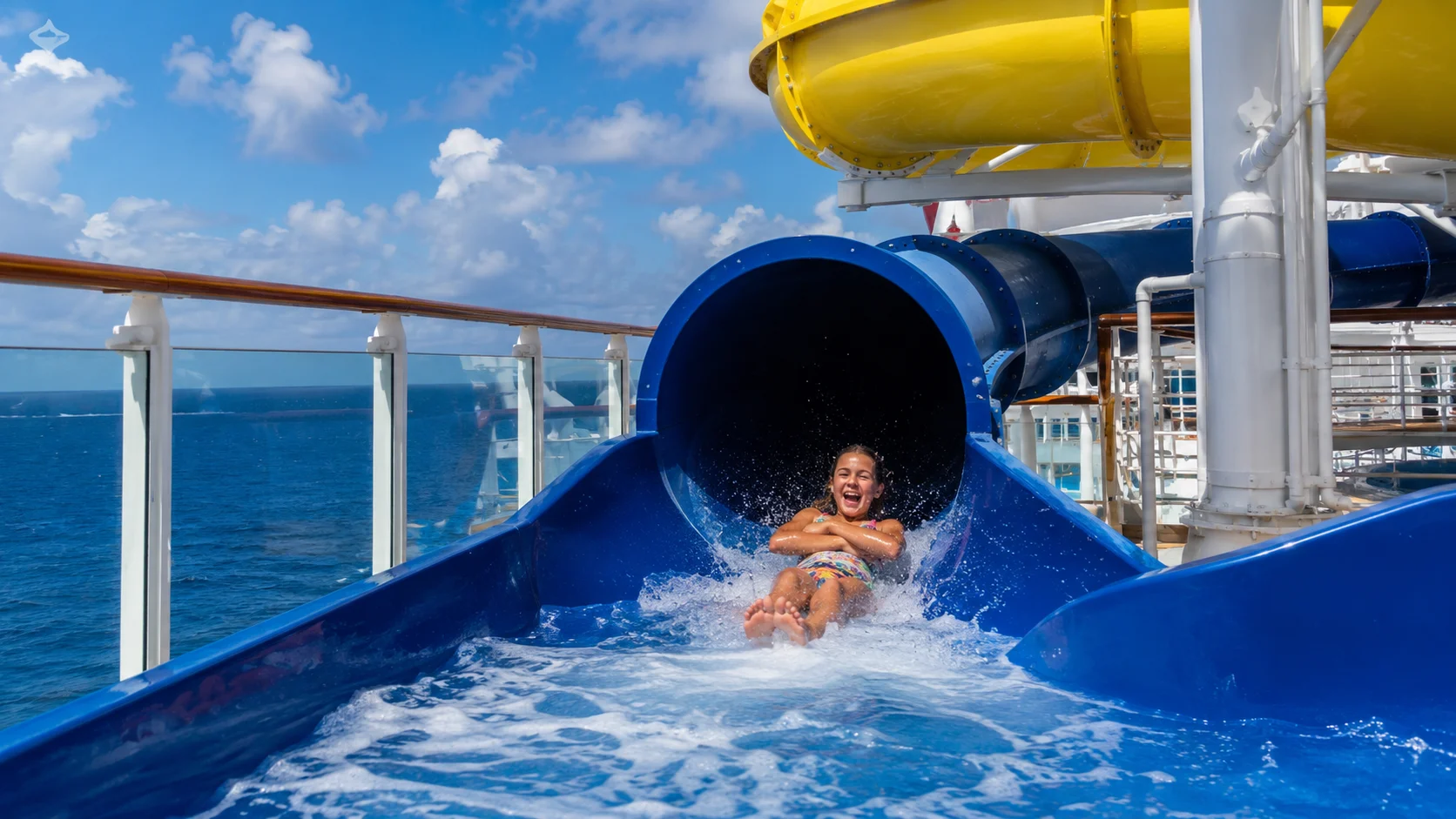 Passenger emerging from a blue waterslide on a cruise ship