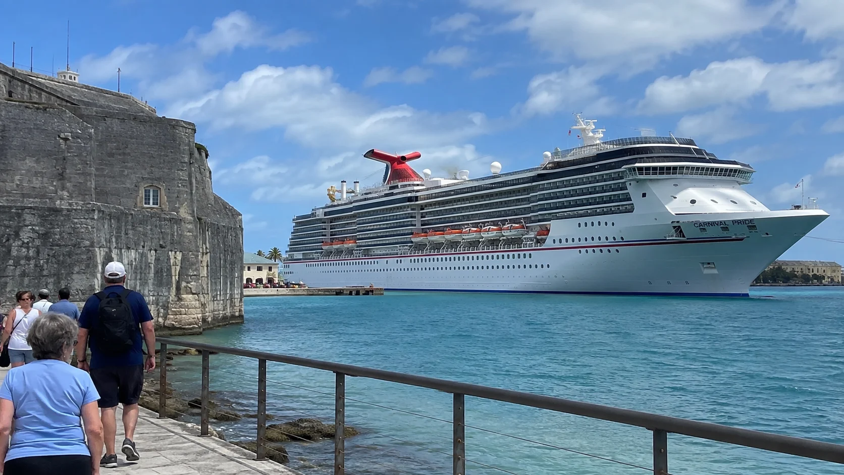 Carnival cruise ship docked beside an old stone waterfront fort