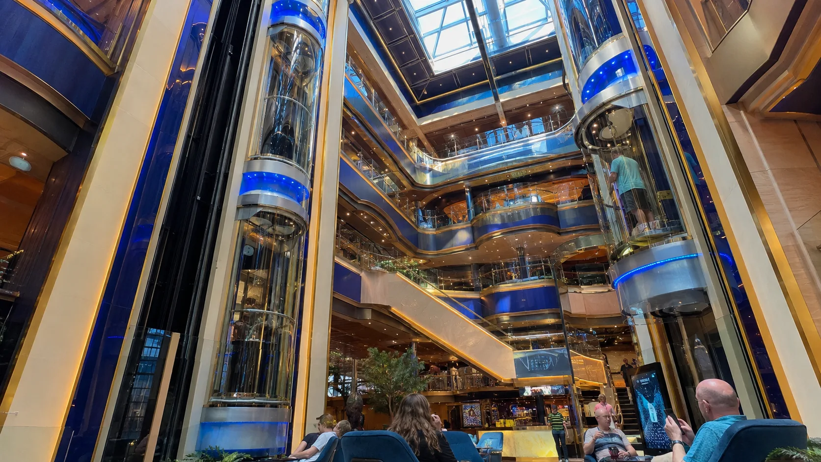 Blue-lit glass elevators and balconies beneath an atrium skylight