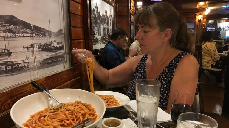 Woman eating pasta in a wood-paneled restaurant