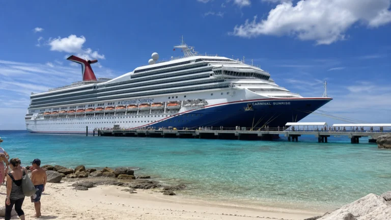 Carnival cruise ship docked beside a sandy tropical beach