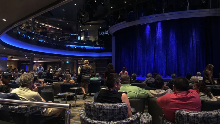 Audience waiting before a blue curtain in a cruise ship lounge