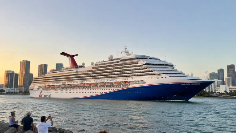 Carnival cruise ship sailing past a waterfront city skyline