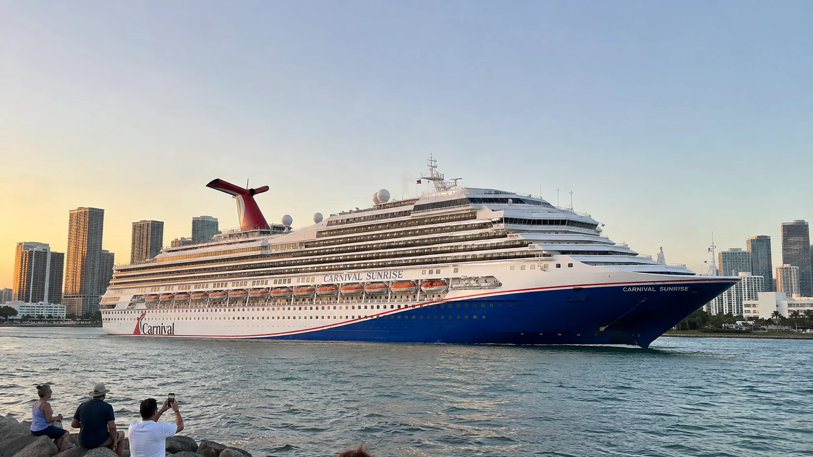 Carnival cruise ship sailing past a waterfront city skyline