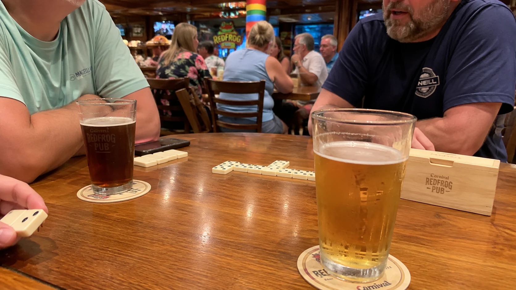 Passengers seated around a table at RedFrog Pub aboard Carnival Sunrise