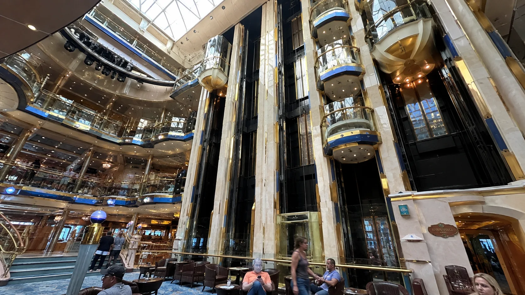 Glass elevators rising through a bright multilevel cruise ship atrium