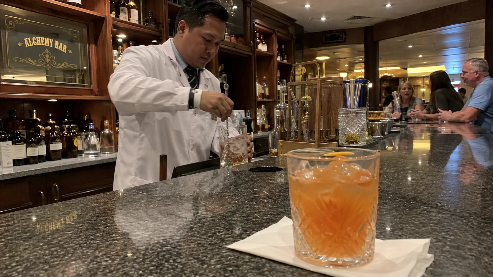 Bartender preparing drinks behind the Alchemy Bar aboard Carnival Valor