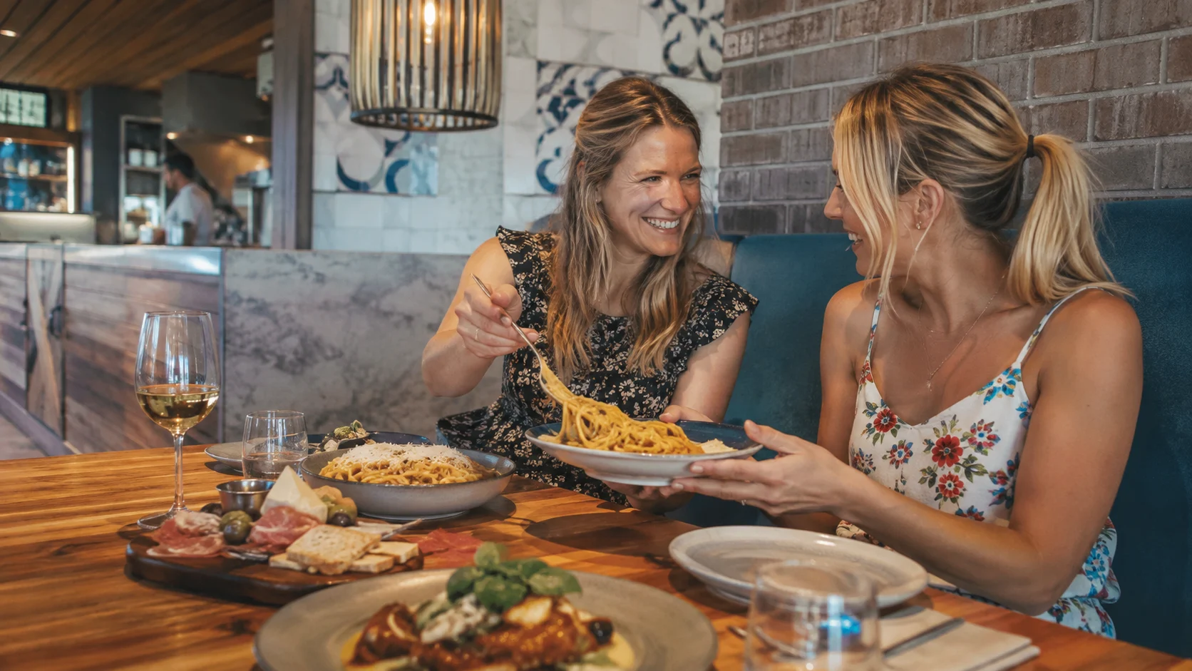 Two diners sharing pasta and antipasti in an Italian restaurant