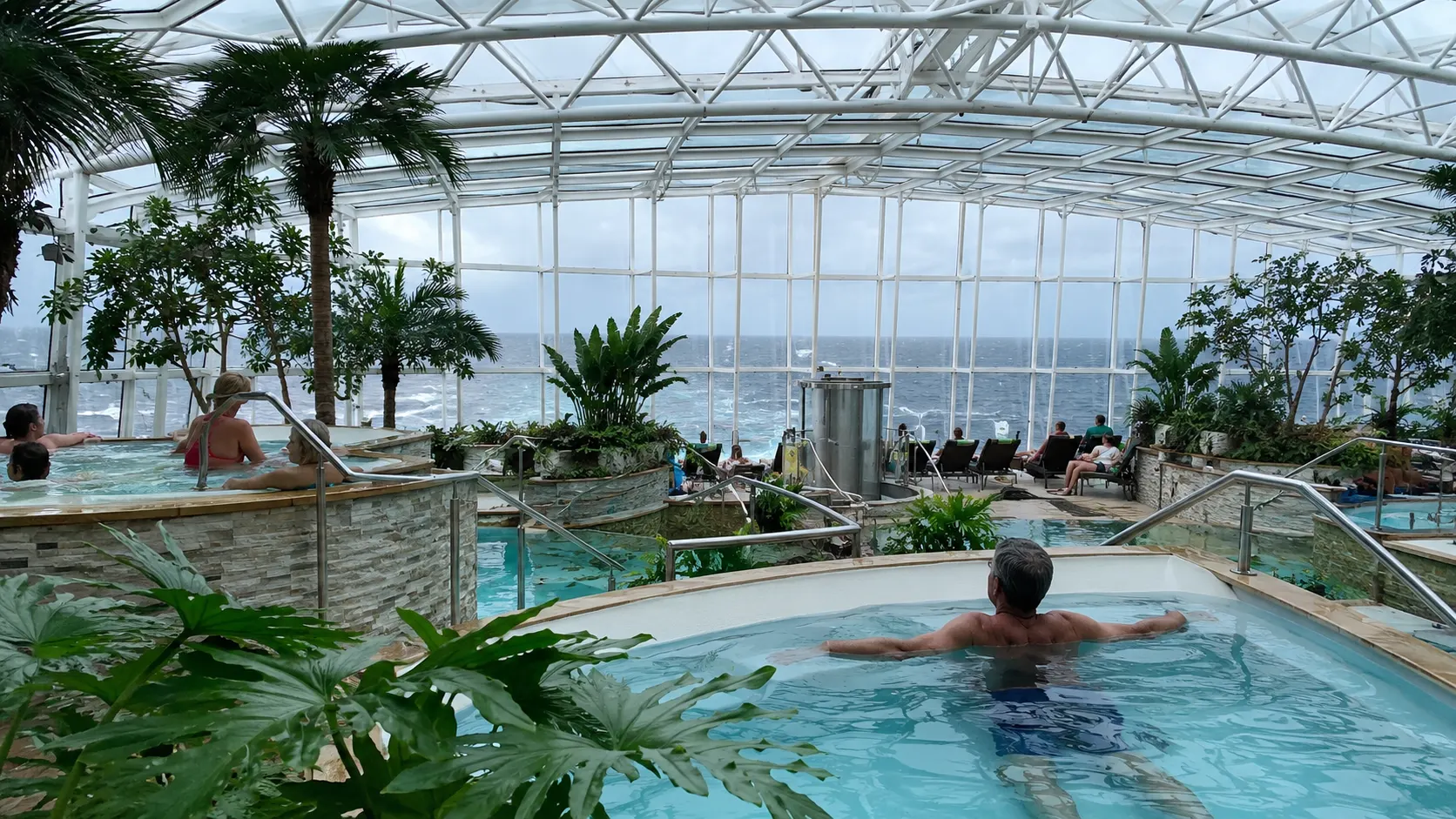 Guests relaxing in Ovation of the Seas glass-roofed Solarium