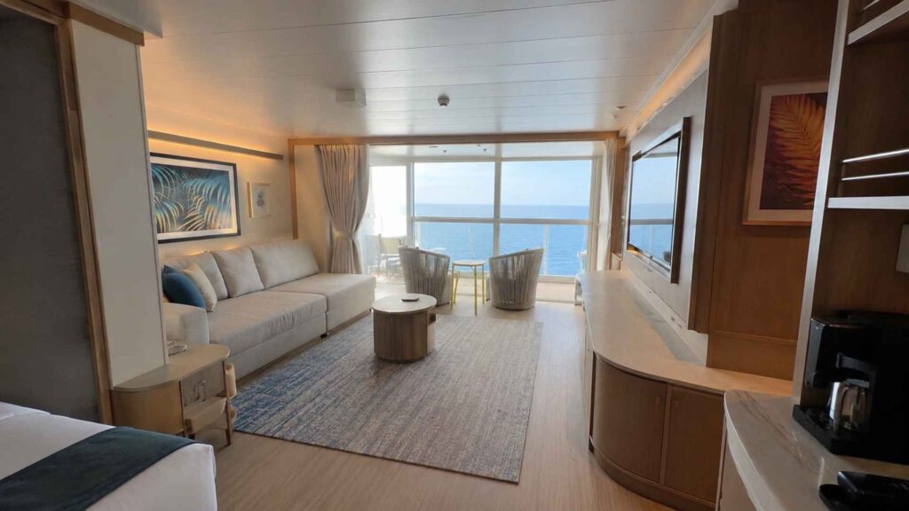 Suite living area on Star of the Seas with a sofa, coffee table and doors onto the balcony