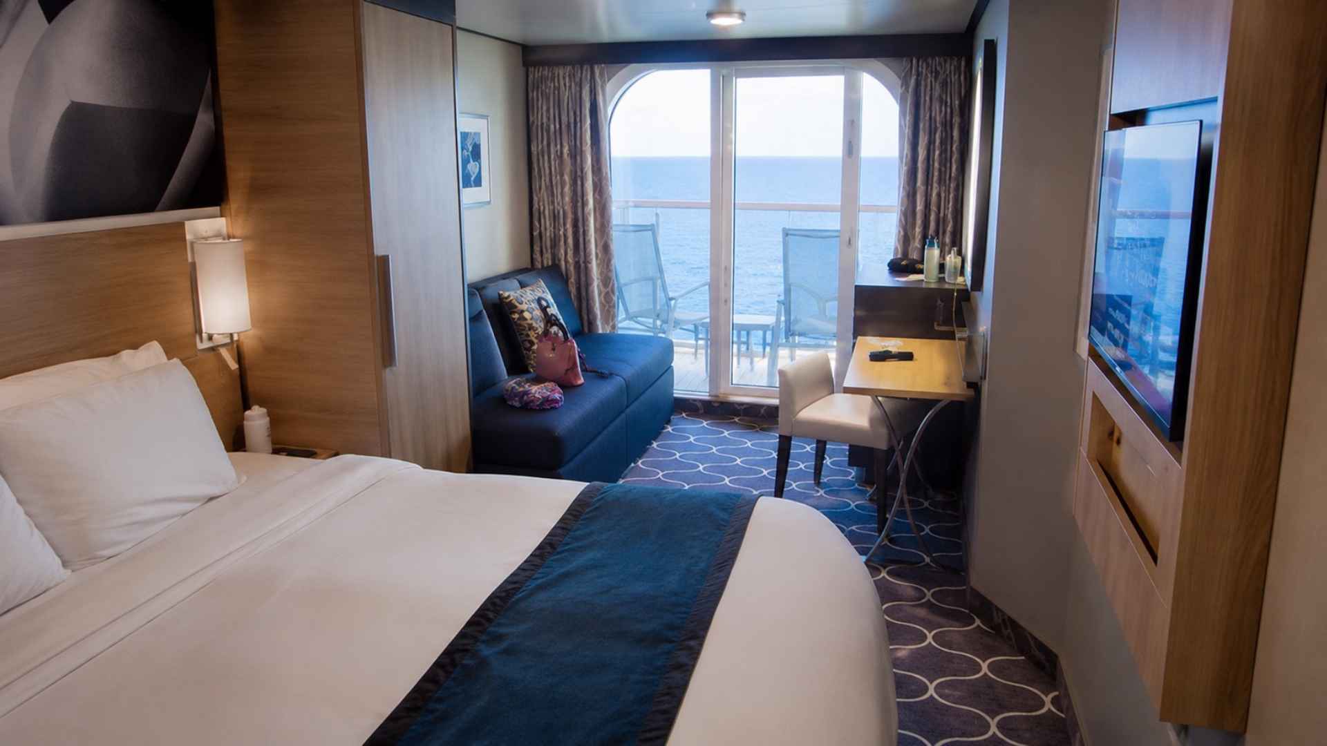 Balcony cabin on Wonder of the Seas with a blue armchair and glass doors onto the balcony