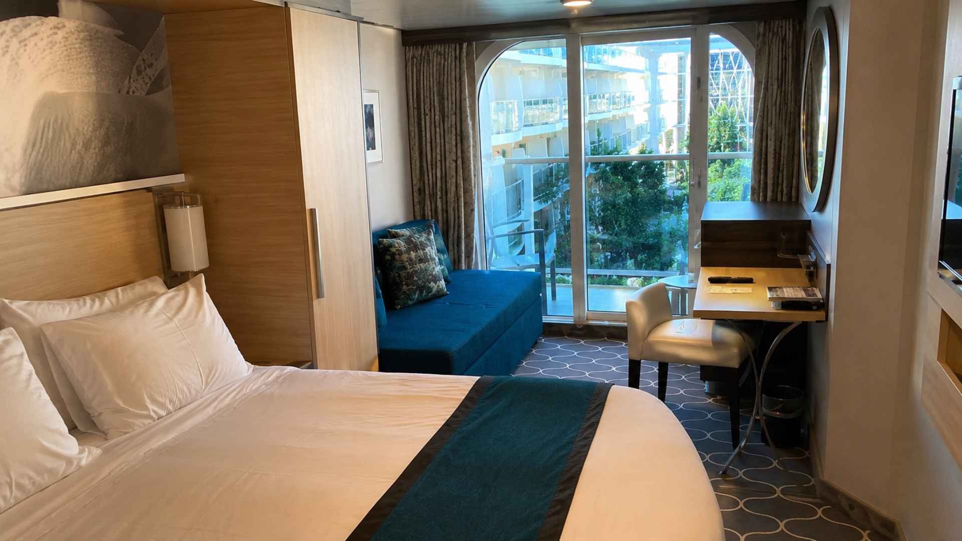 Balcony cabin on Wonder of the Seas with a desk, seating area and curtained balcony doors